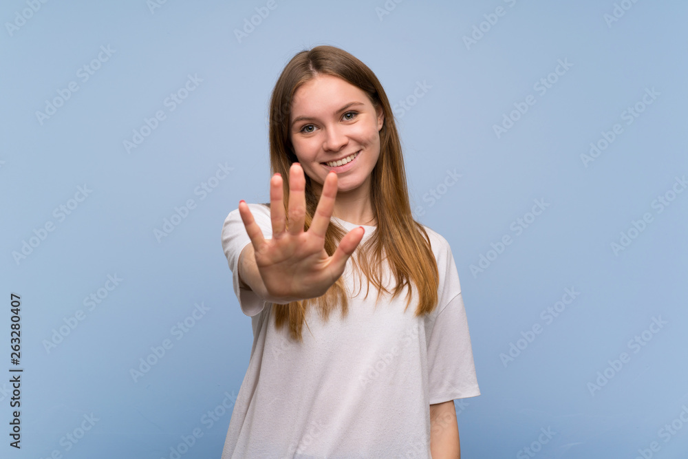 Young woman over blue wall counting five with fingers Young woman over blue wall counting five with fingers