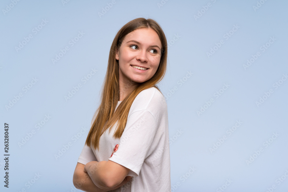 Young woman over blue wall with arms crossed Young woman over blue wall with arms crossed