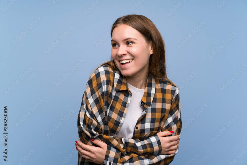 Young woman over blue wall laughing