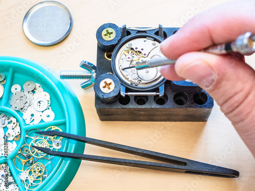watchmaker repairs mechanical watch by screwdriver
