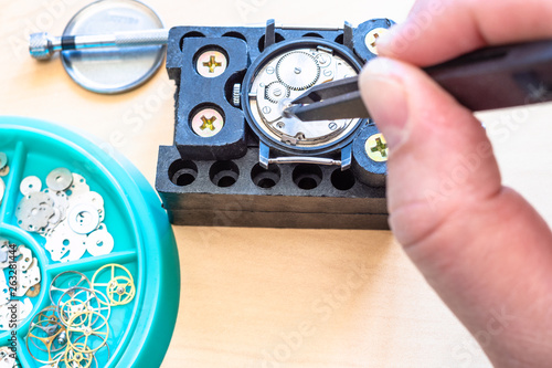 watchmaker repairs mechanical watch with tweezers