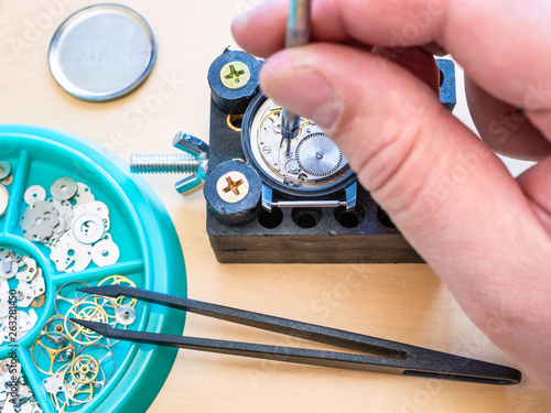 watchmaker adjusts mechanical watch by screwdriver