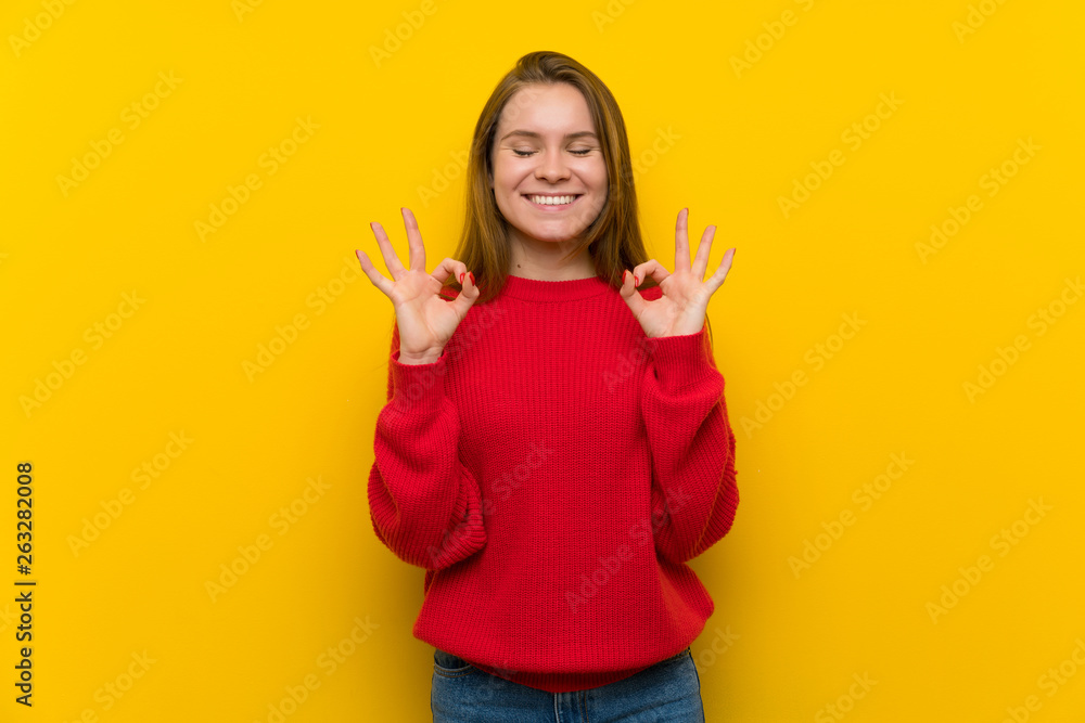 Young woman over yellow wall in zen pose Young woman over yellow wall in zen pose