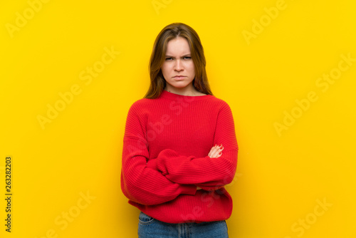 Young woman over yellow wall feeling upset
