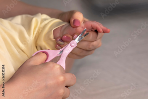 Mother cuts .her small child fingernails with protected scissors. Close-up. © Danil Bukharov
