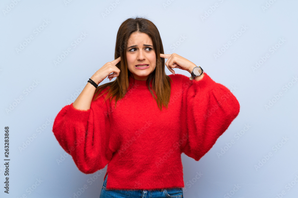 Young woman over isolated blue wall frustrated and covering ears Young woman over isolated blue wall frustrated and covering ears