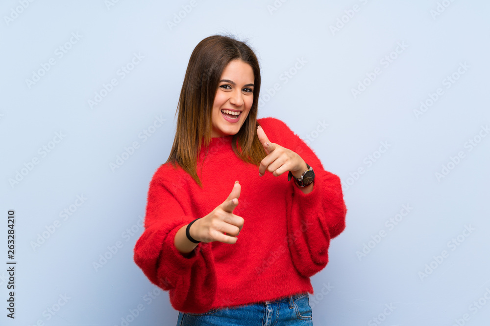 Young woman over isolated blue wall pointing to the front and smiling Young woman over isolated blue wall pointing to the front and smiling