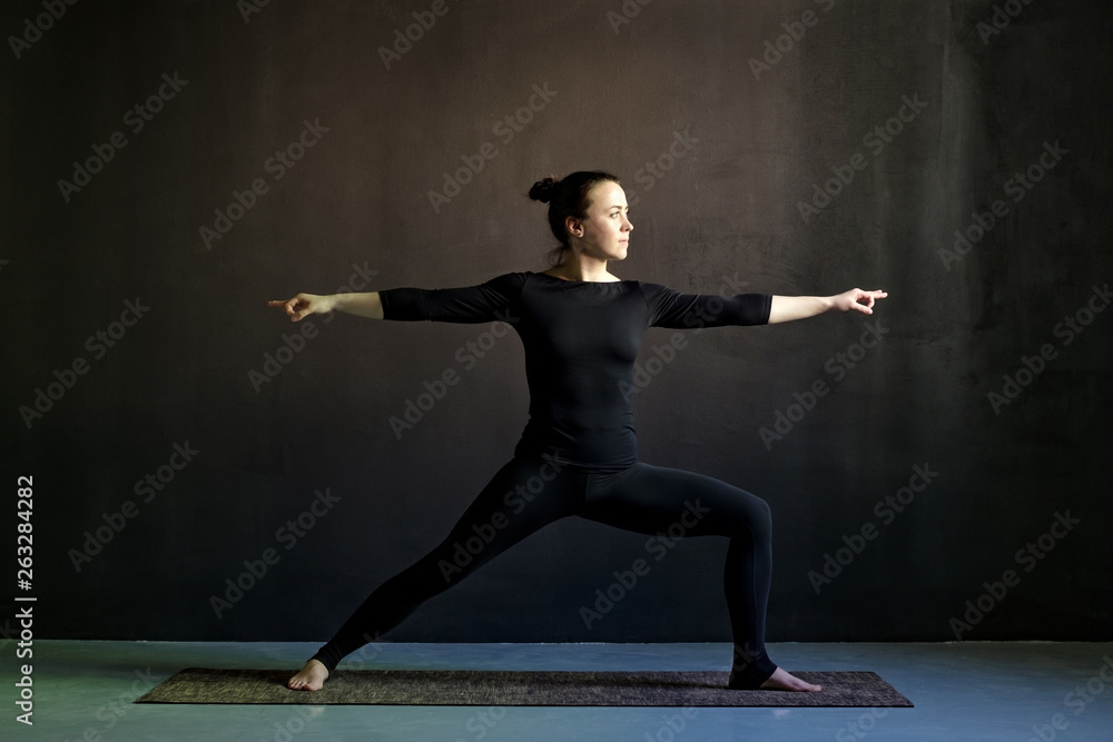 Young woman practicing yoga Warrior pose, Virabhadrasana.