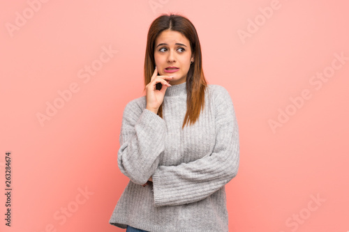 Young woman over pink wall with confuse face expression