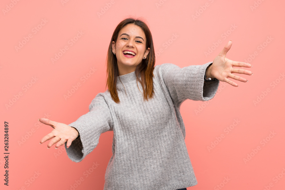 Young woman over pink wall presenting and inviting to come with hand Young woman over pink wall presenting and inviting to come with hand