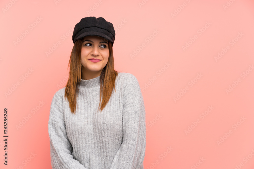 Fashion woman with hat over pink wall standing and looking to the side Fashion woman with hat over pink wall standing and looking to the side