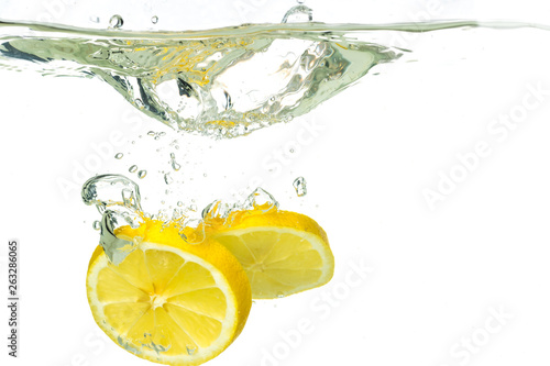 lemon slices and lime falling into water and splash on white background