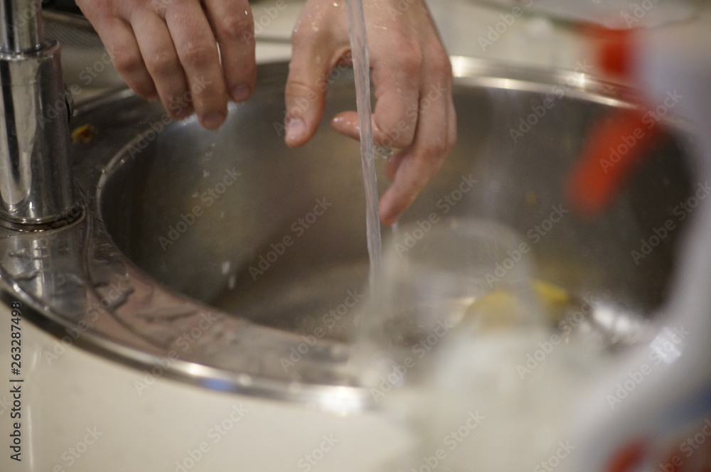 man washing dishes in kitchen