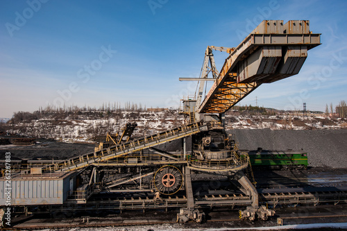 delivery of iron ore by a conveyor belt from a warehouse and loading into railway dump cars.