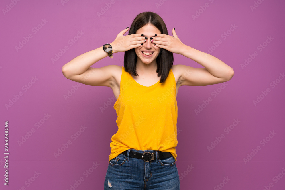 Young woman over isolated purple wall covering eyes by hands Young woman over isolated purple wall covering eyes by hands