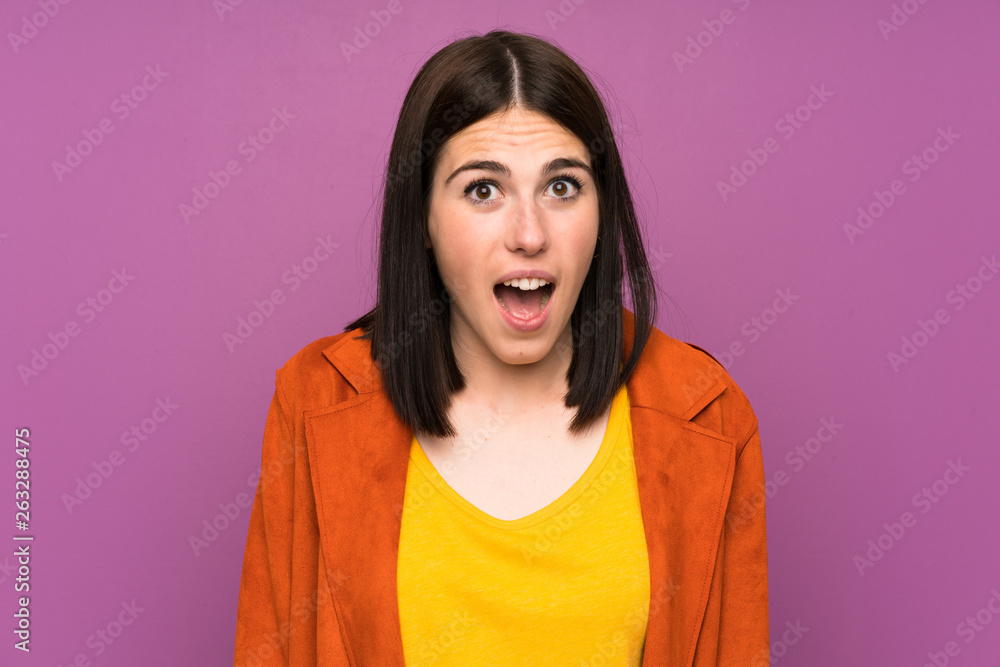 Young woman with a coat over isolated purple background with surprise facial expression Young woman with a coat over isolated purple background with surprise facial expression