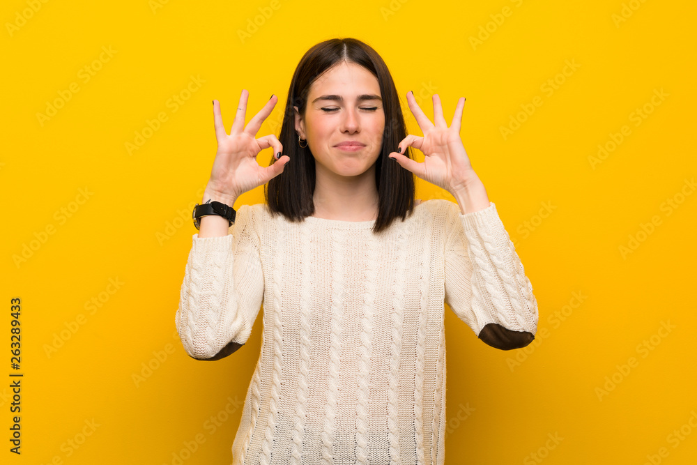 Young woman over isolated yellow wall in zen pose Young woman over isolated yellow wall in zen pose