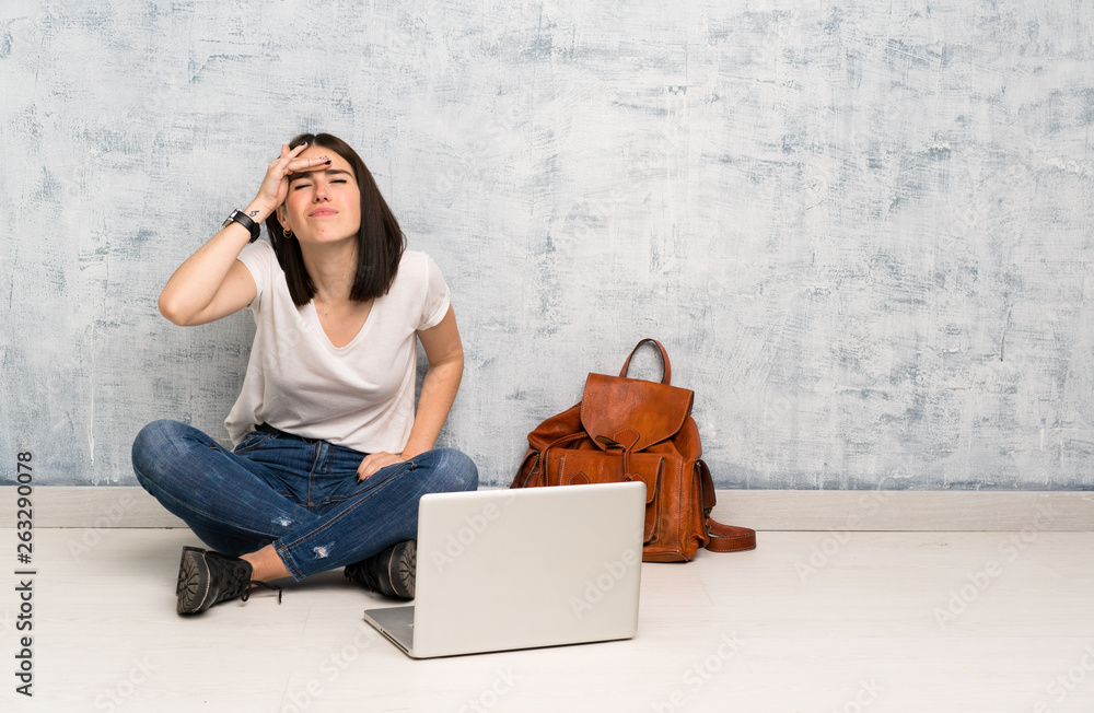 Student woman sitting on the floor looking far away with hand to look something Student woman sitting on the floor looking far away with hand to look something