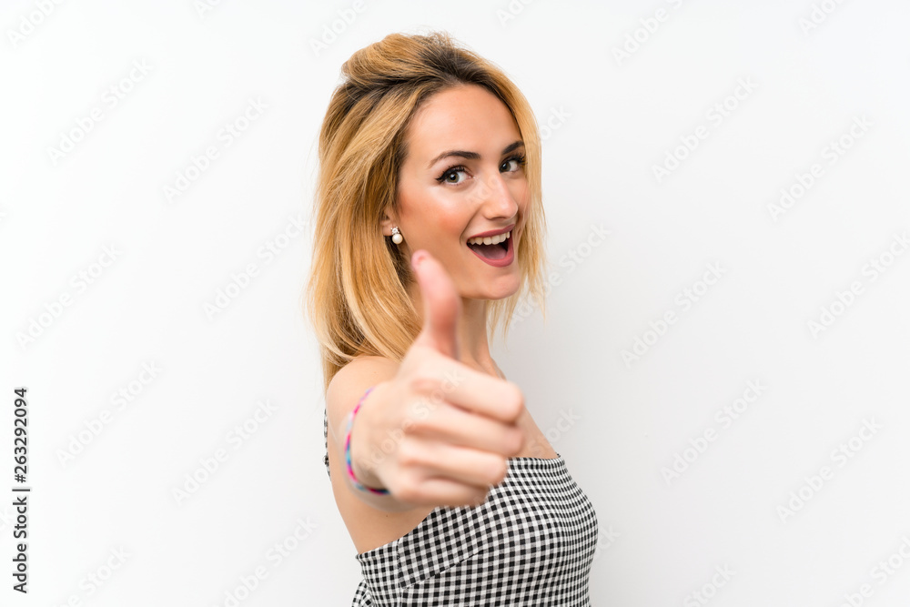 Young blonde woman over isolated white with thumbs up because something good has happened Young blonde woman over isolated white with thumbs up because something good has happened