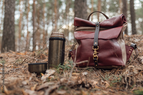 a thermos of tea and a backpack in the woods