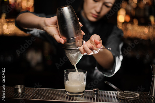 Close shot of bartender preparing cocktail adding sour mix in glass