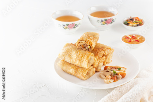 Traditional Chinese tortillas filled - bings in a plate with mushrooms on a white background, cups of tea. Copy space