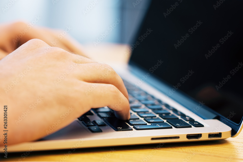 Sideview of male using laptop on desk Sideview of male using laptop on desk