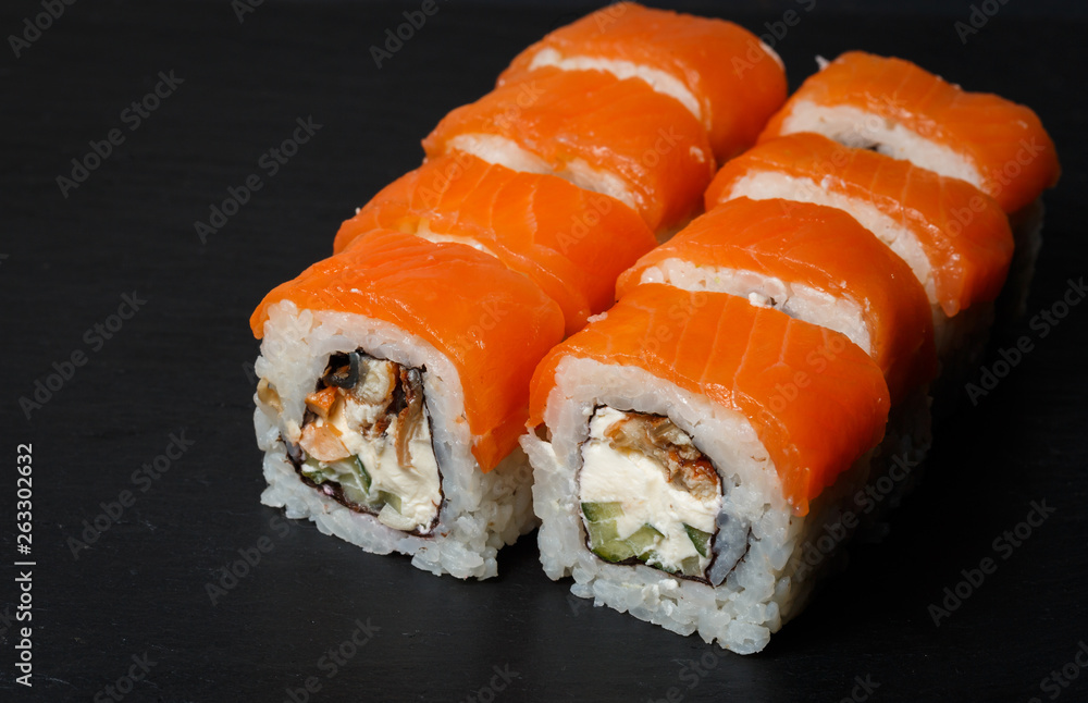 Philadelphia roll sushi with salmon, avocado, cream cheese served on black stone slate Philadelphia roll sushi with salmon, avocado, cream cheese served on black stone slate