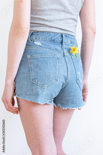 Spring style. woman with  yellow daffodil in pocket of jeanson white background