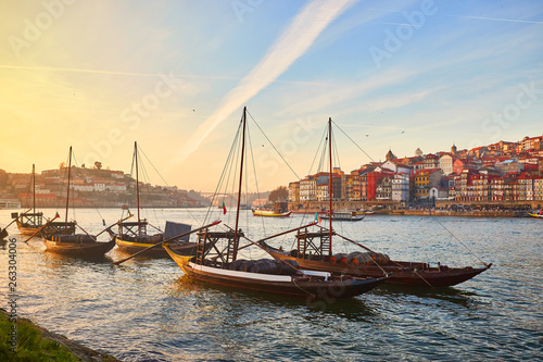 Typowe portugalskie drewniane łodzie, zwane „barcos rabelos”, przewożące beczki z winem na rzece Douro z widokiem na Villa Nova de Gaia w Porto, Portugalia