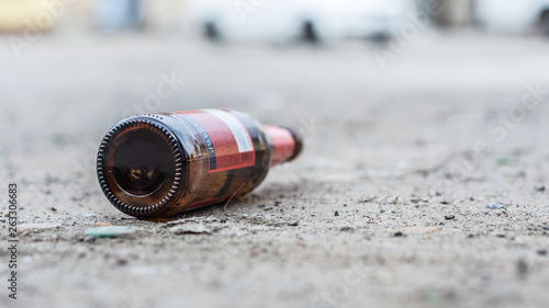 A glass bottle of beer littering on the ground