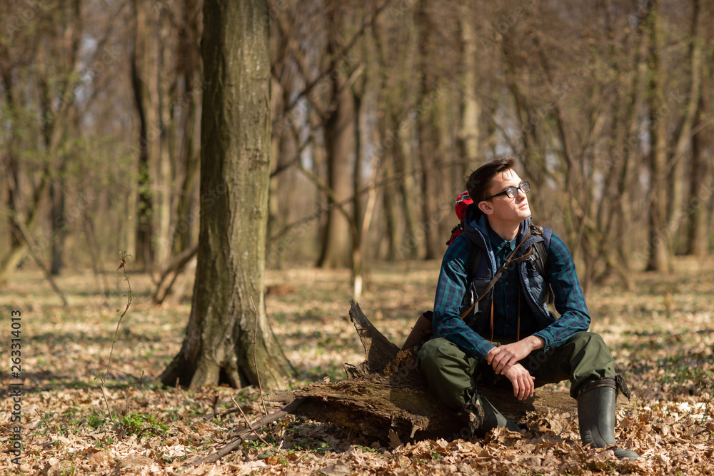 Young man with backpack hiking in the forest. Nature and physical exercise concept Young man with backpack hiking in the forest. Nature and physical exercise concept
