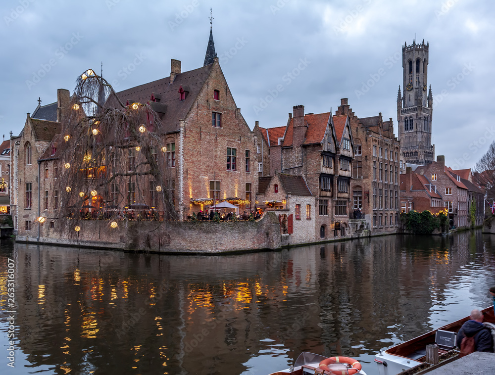 The Rozenhoedkaai (Quay of the Rosary) canal in Bruges with the classic medieval buildings and Belfry of Bruges in the background. Quay of the Rosary in the evening.