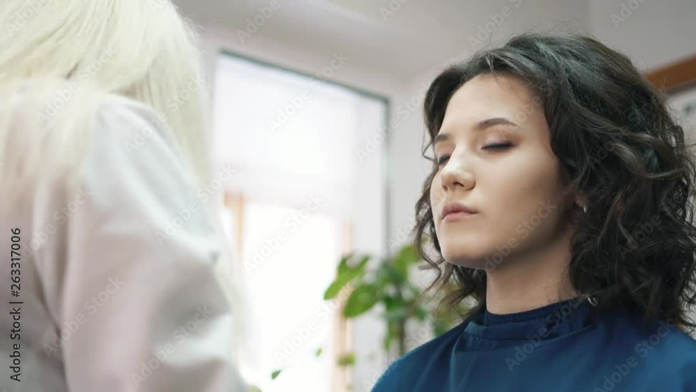 Beautiful Woman Make-up Artist Paints The Eyes Of A Charming Young Brunette Beautiful Woman Make-up Artist Paints The Eyes Of A Charming Young Brunette