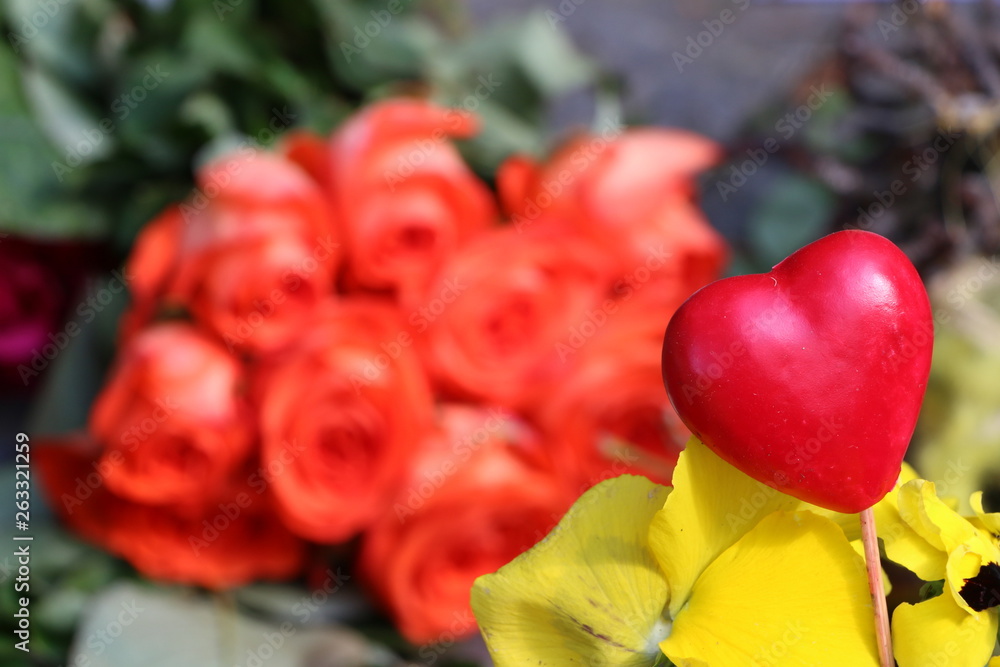 Rotes Herz, im Hintergrund etwas unscharf ein Strauß mit roten Rosen; Symbole für Muttertag, Liebe, Freundschaft, Valentinstag Rotes Herz, im Hintergrund etwas unscharf ein Strauß mit roten Rosen; Symbole für Muttertag, Liebe, Freundschaft, Valentinstag