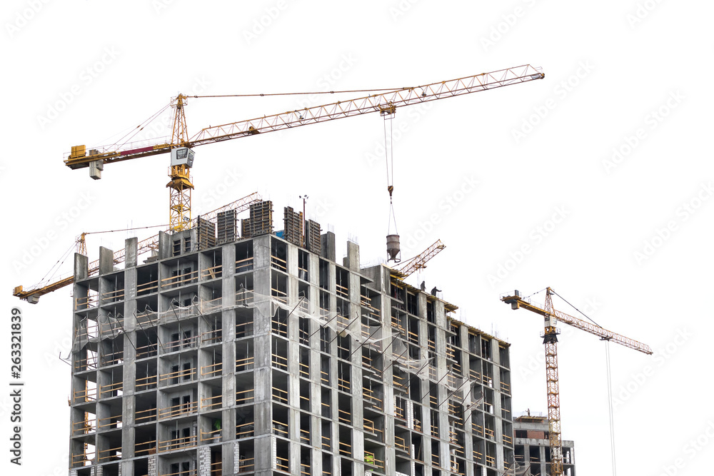 High-rise building crane with a long arrow of yellow color on a white background above a concrete building under construction with brick walls High-rise building crane with a long arrow of yellow color on a white background above a concrete building under construction with brick walls