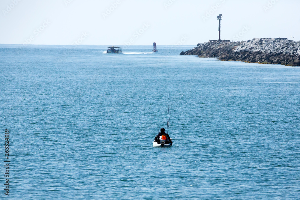 Person in a small boat heads out to fish in the bay