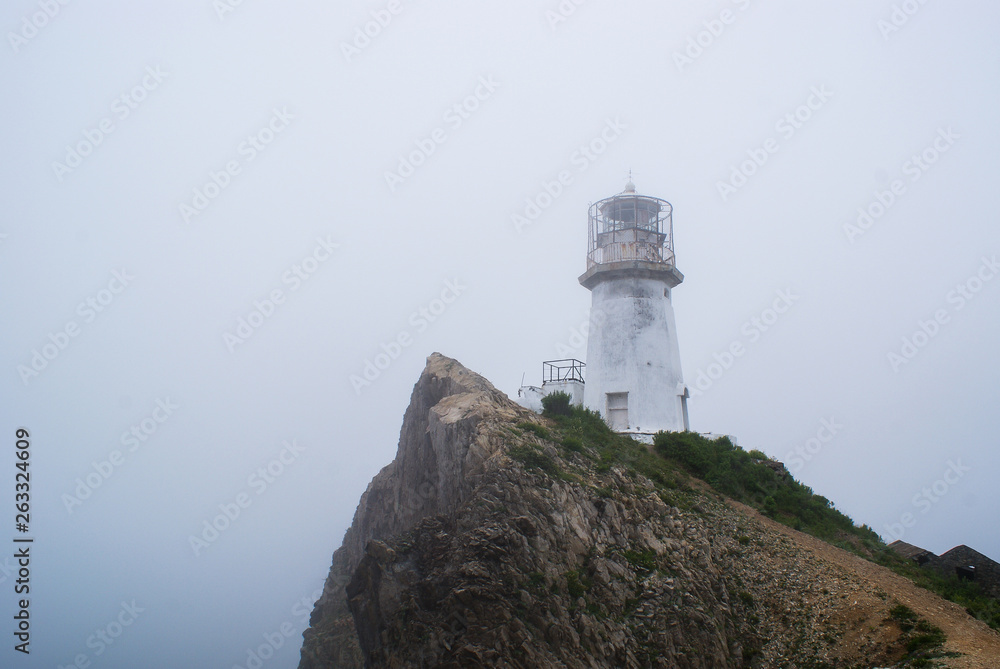 Cape Briner. Primorsky Krai. At the top of the cliff, there is an old lighthouse hidden in the fog