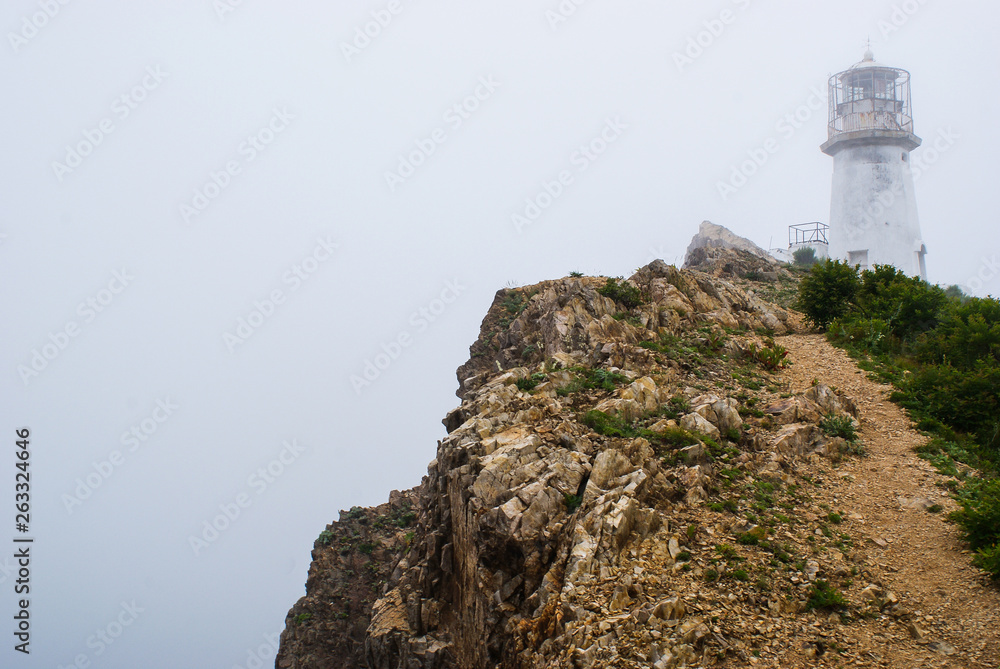 Cape Briner. Primorsky Krai. At the top of the cliff, there is an old lighthouse hidden in the fog Cape Briner. Primorsky Krai. At the top of the cliff, there is an old lighthouse hidden in the fog