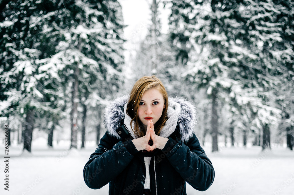 Portrait of a beautiful girl in the black jacket with fur hood amid winter forest Portrait of a beautiful girl in the black jacket with fur hood amid winter forest