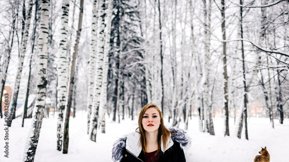 Portrait of a beautiful girl in the black jacket with fur hood amid winter forest Portrait of a beautiful girl in the black jacket with fur hood amid winter forest