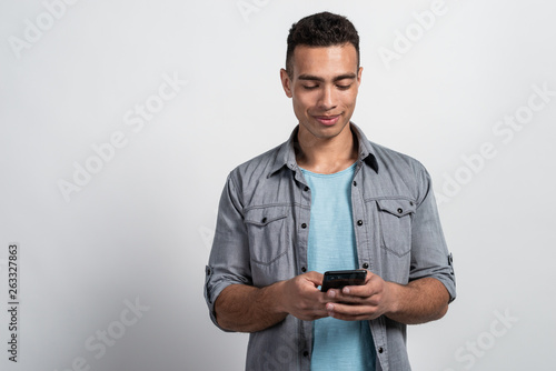 Half-length portrait of a man standing against the white background holding mobile phone in his hands © speed300