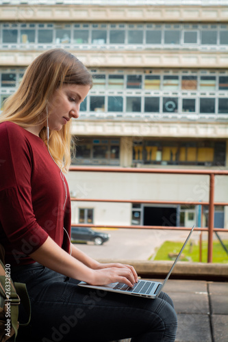 Young student using laptop outdoors.