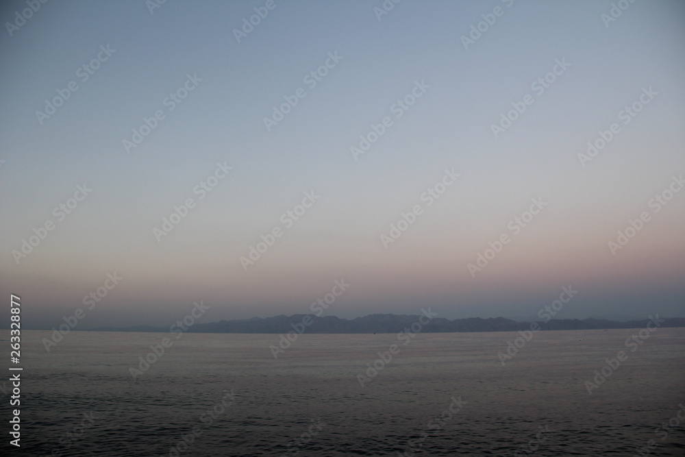 twilight over the sea with mountains on the horizon twilight over the sea with mountains on the horizon
