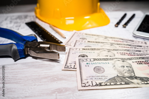Construction industry costs money us dollars banknotes by tools safety equipment and blueprints © Miljan Živković
