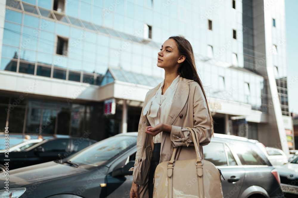Fototapeta premium Office worker girl goes after work along buildings