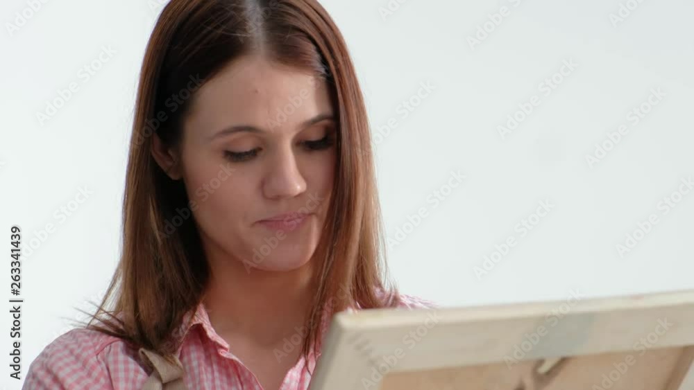 Young beautiful woman painter among easels and canvases in a bright studio. Inspiration and hobby. Drawing a pencil, graphics. Young beautiful woman painter among easels and canvases in a bright studio. Inspiration and hobby. Drawing a pencil, graphics.