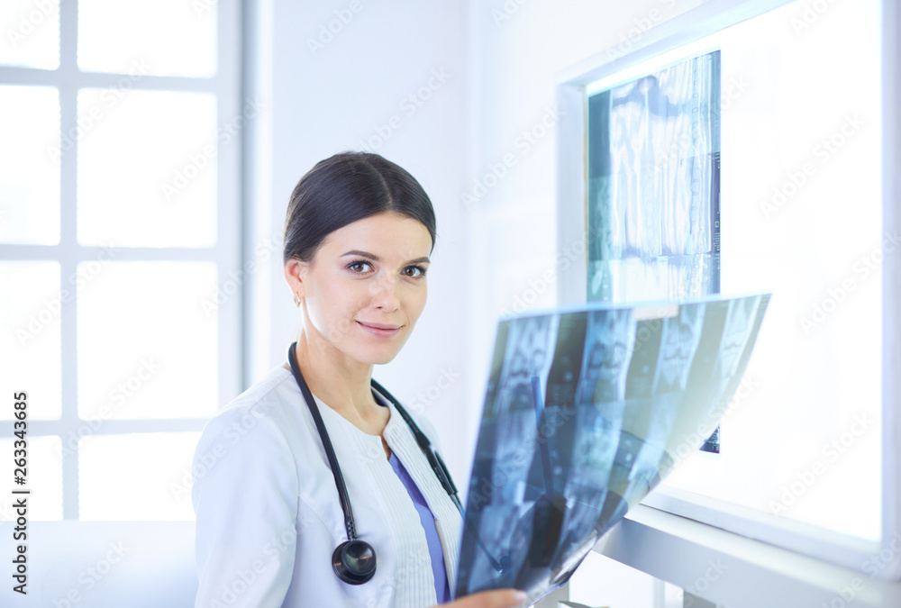 Young female doctor with stethoscope examining X-ray at doctor's office Young female doctor with stethoscope examining X-ray at doctor's office
