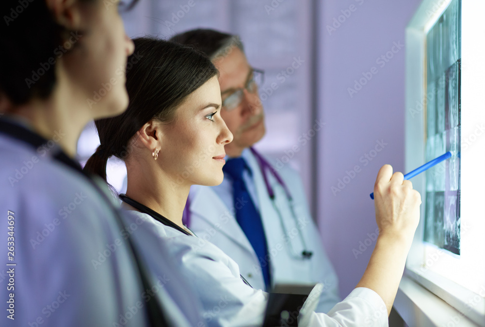 Group of doctors examining x-rays in a clinic, thinking of a diagnosis Group of doctors examining x-rays in a clinic, thinking of a diagnosis