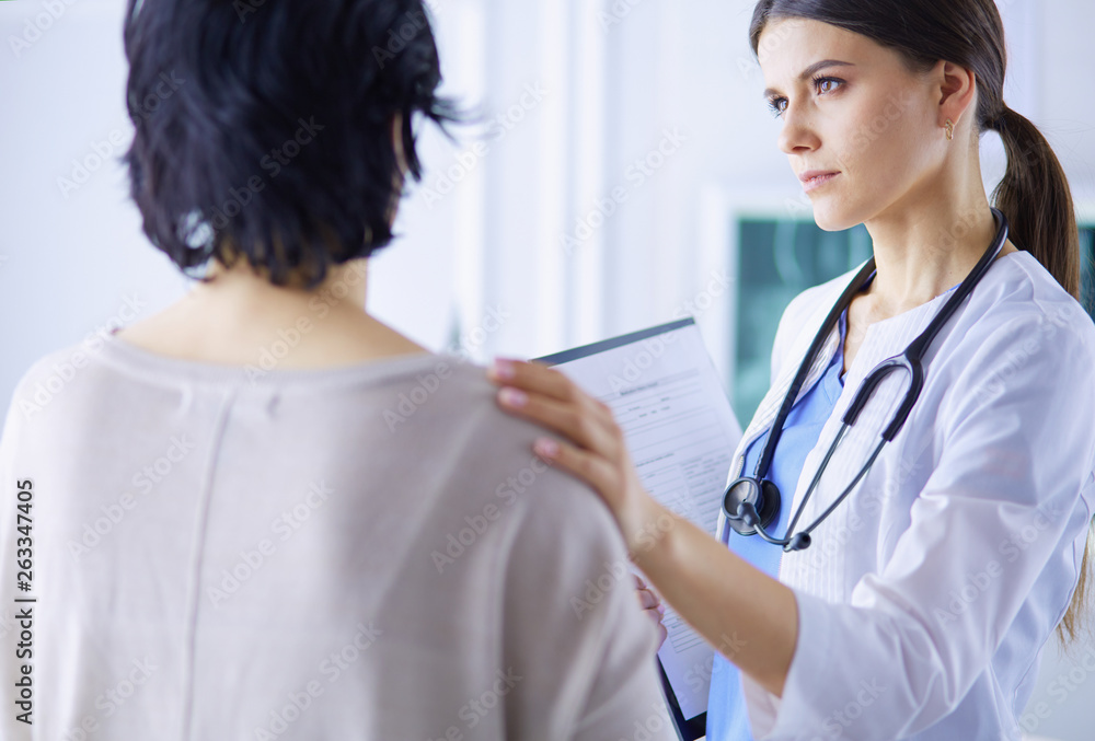 Medical consultation. Female doctor holding a patient by her shoulder, soothing her fear Medical consultation. Female doctor holding a patient by her shoulder, soothing her fear